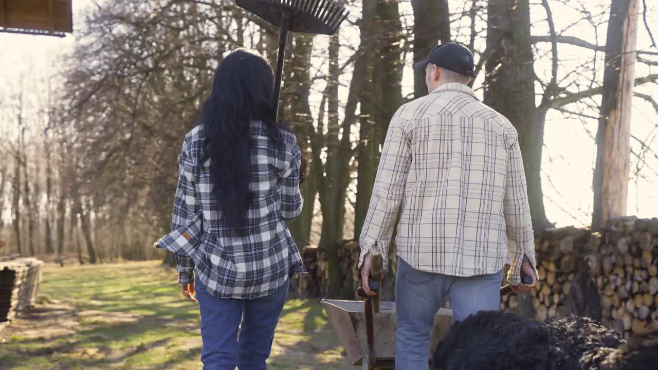 Rear view of caucasian couple and their dog walking throught the countryside The man is carrying a wheelbarrow