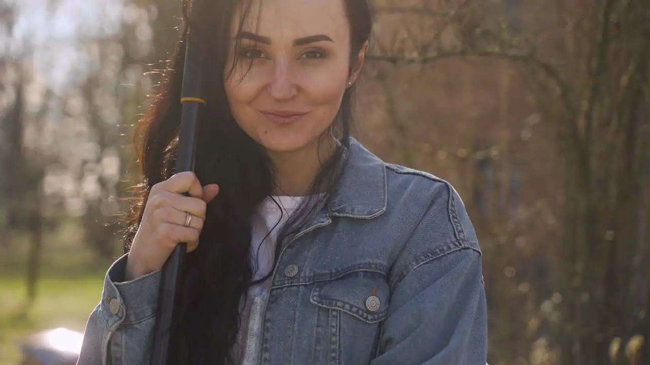 Close-up view of caucasian woman holding a rake and smiling at camera in the countryside