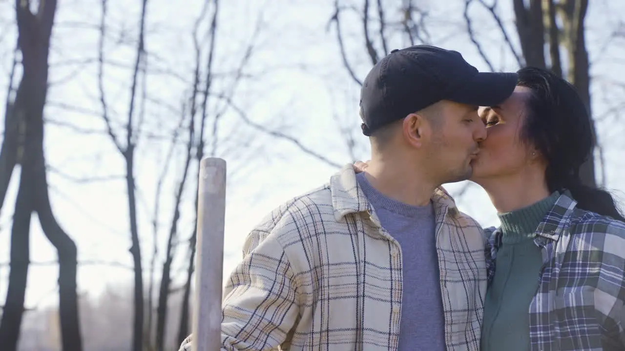 Close-up view of a man is removing weeds in the countryside The his partner approachs and kisses him