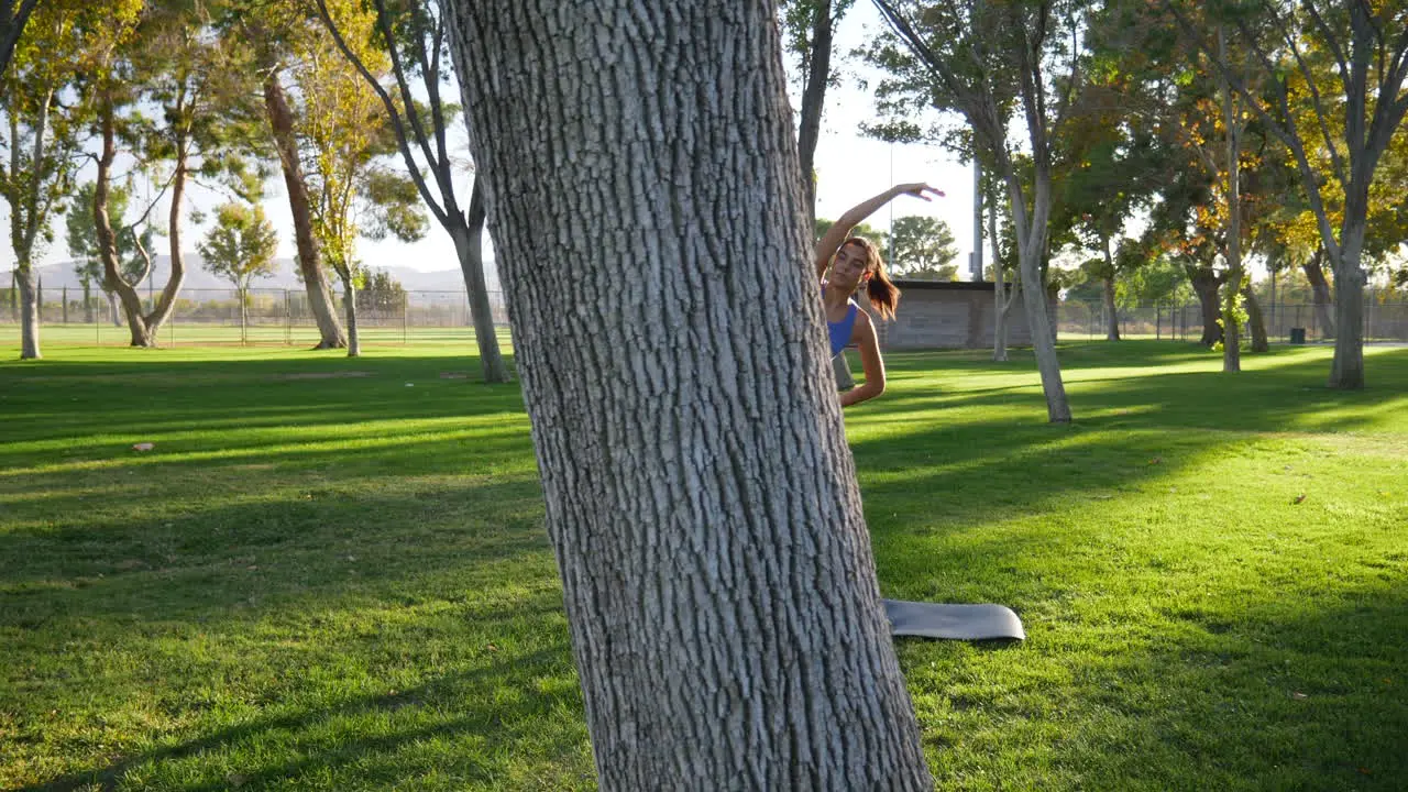 A pretty young hispanic woman stretching and loosening up her body before a workout in the park at sunset SLOW MOTION