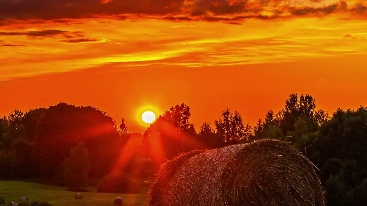 Timelapse view of orange sunset over hilly rural agricultural landscape