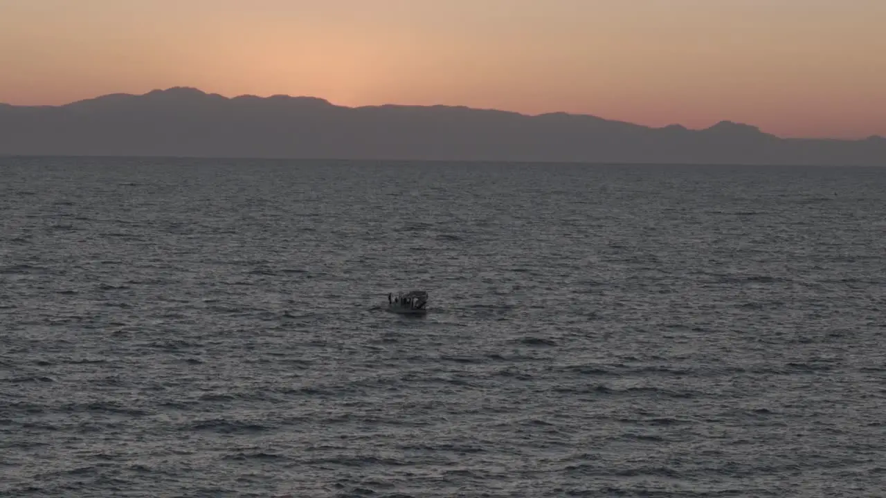 Aerial view rising over sailing boat navigating picturesque Mediterranean sea against glowing orange sunset sky