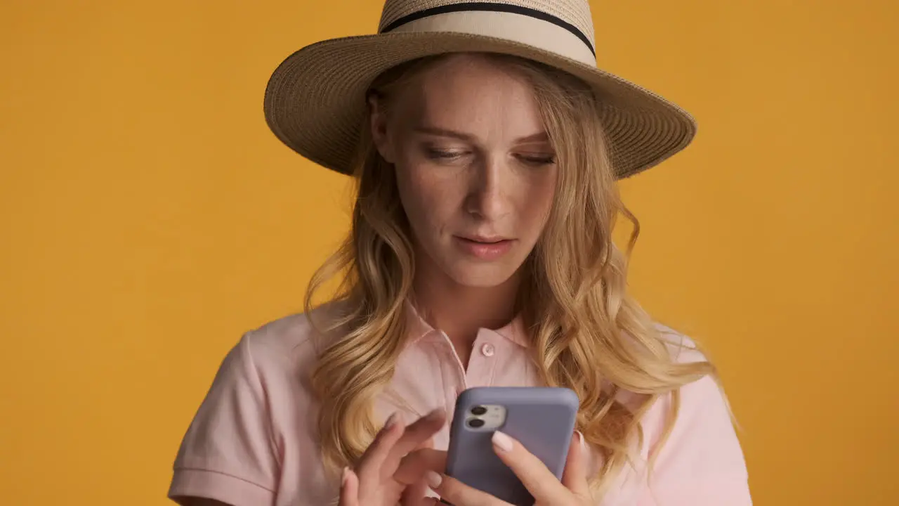 Caucasian woman in a hat texting on smartphone