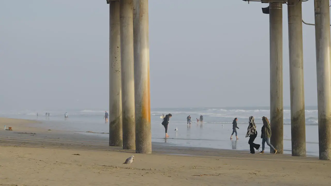 Two girls walking under the pier in Huntington Beach California