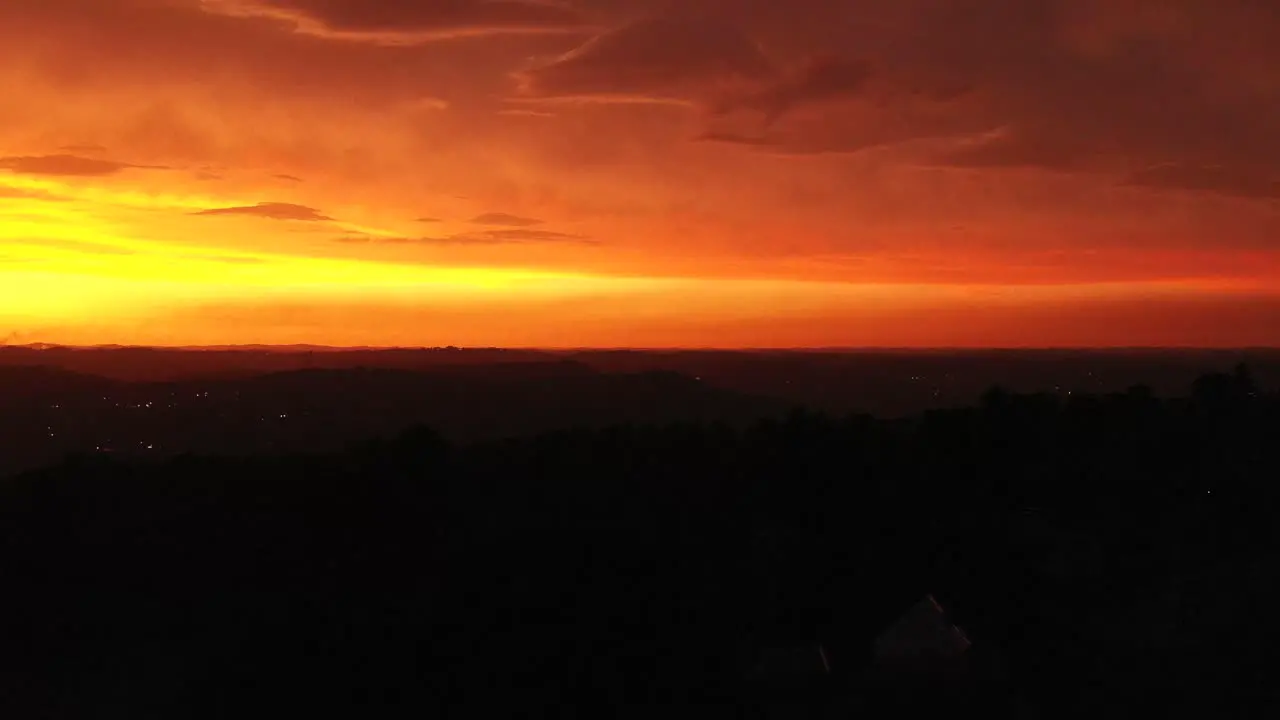 Rising drone shot revealing fiery red and orange sky