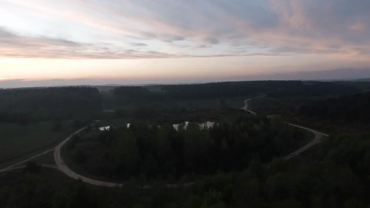 Small lake surrounded by trees at dusk sunset Parallax aerial shot