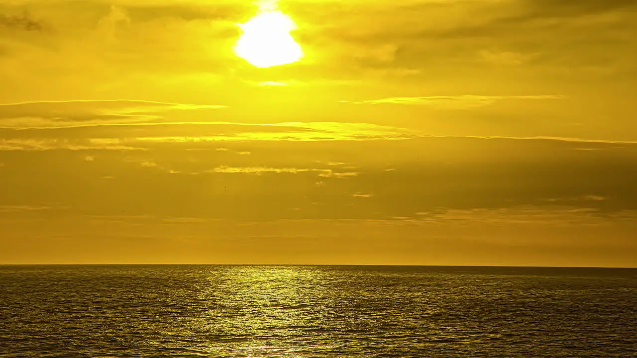 View of sun rising from behind the white clouds in timelapse over the sea water along the coast in Via Molino Italy at dawn