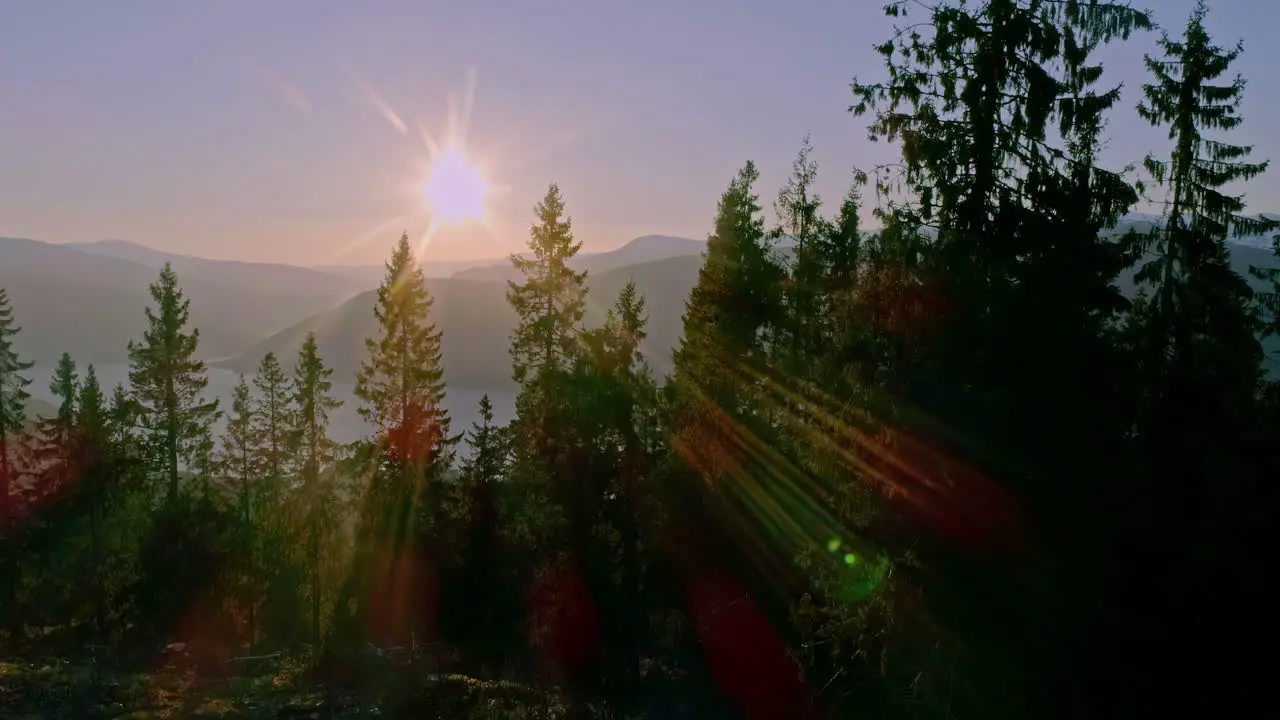 High angle shot over mountain range along fjord in Norway with sun setting in the background