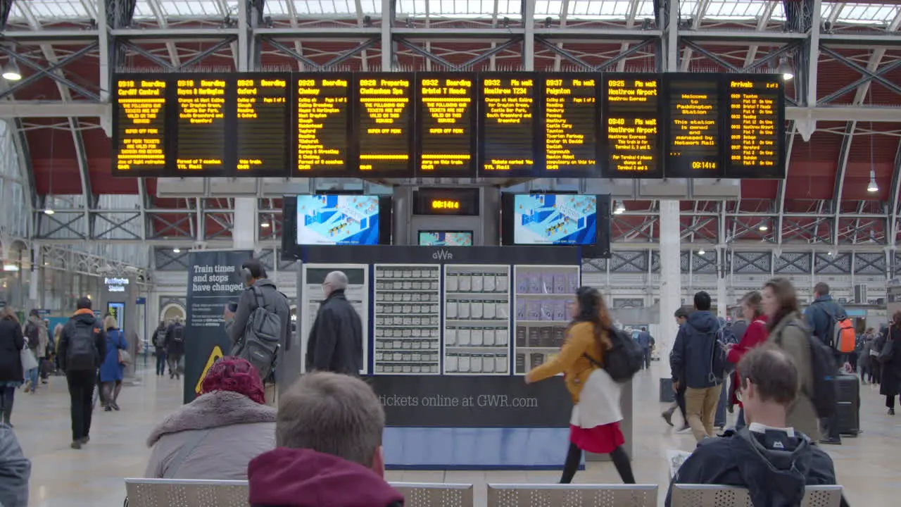 People passing underneath station departure board