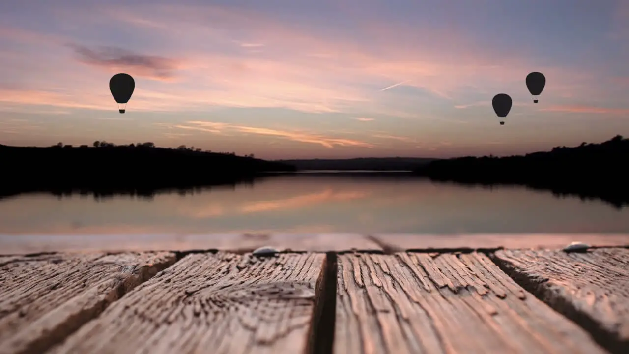 Wooden deck and hot air balloons over a lake