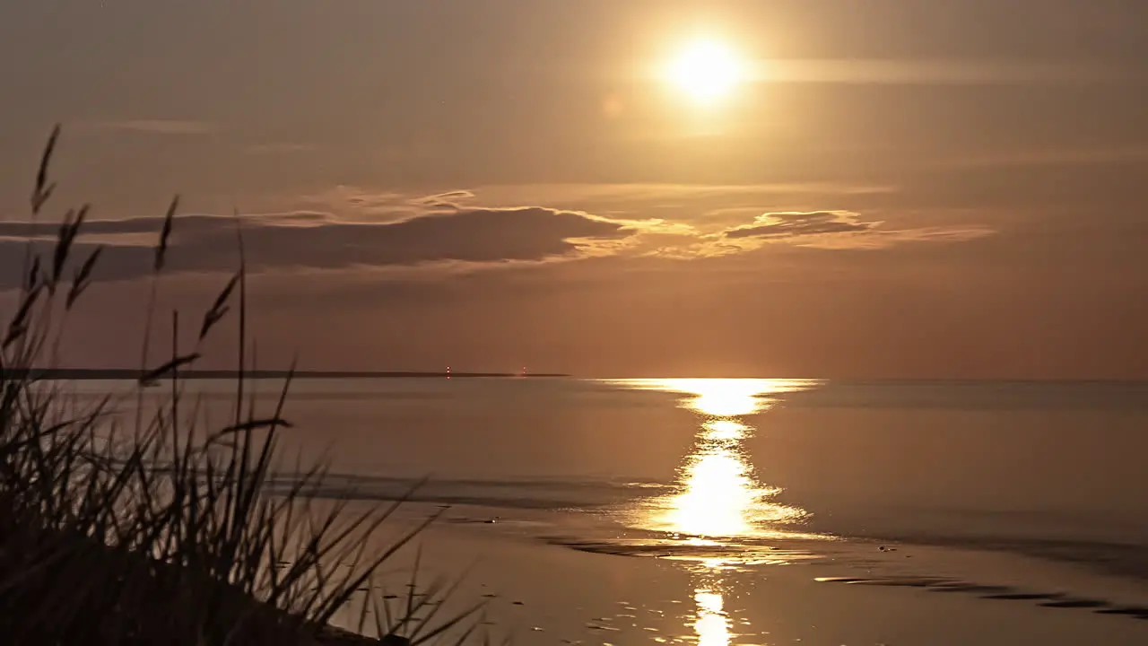 Timelapse of the sun setting over the ocean in the horizon with clouds passing by in the evening