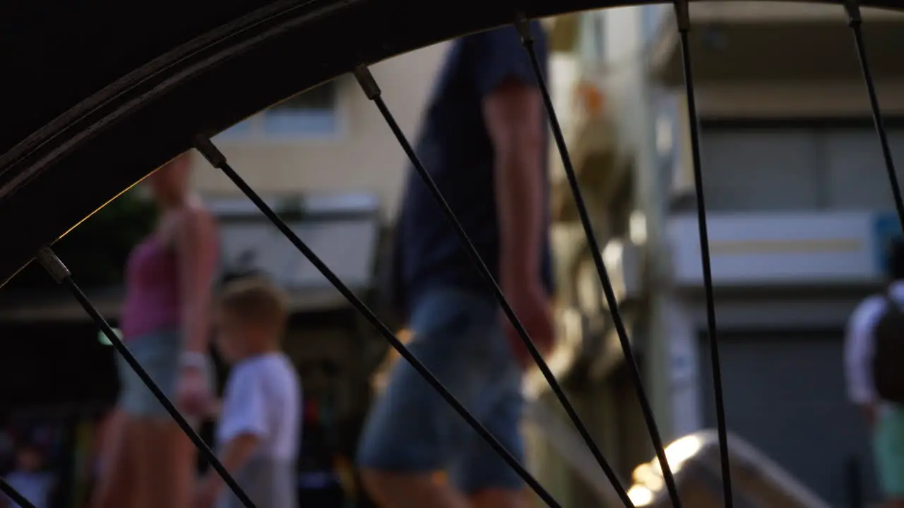 People in the street View against sun flare through the bike wheel