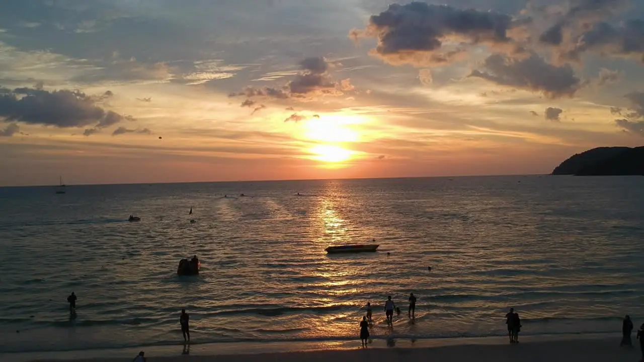 Flying drone from left to right while beautiful sunset reflecting in the ocean at Pantai Cenang in Langkawi Malyasia