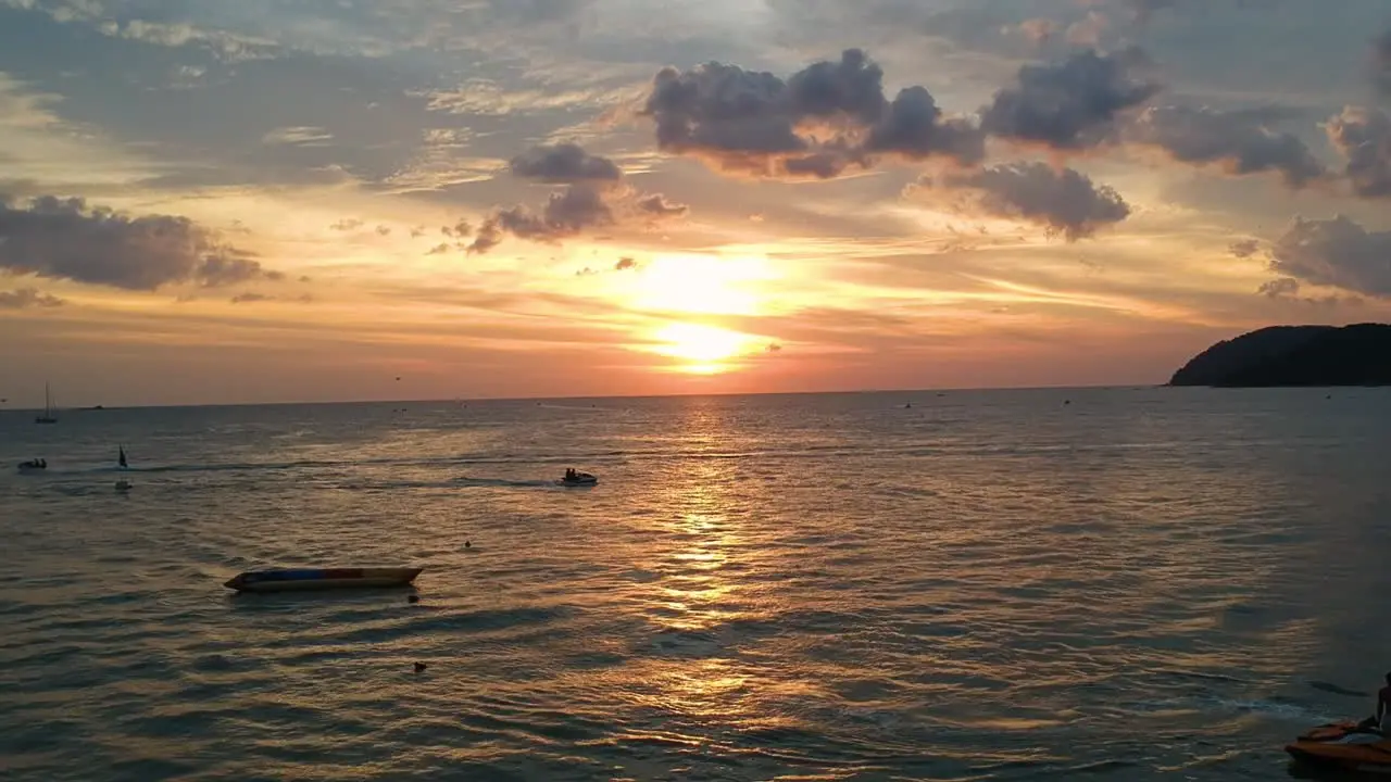 Flying drone into beautiful sunset reflecting in the ocean at Pantai Cenang in Langkawi Malyasia