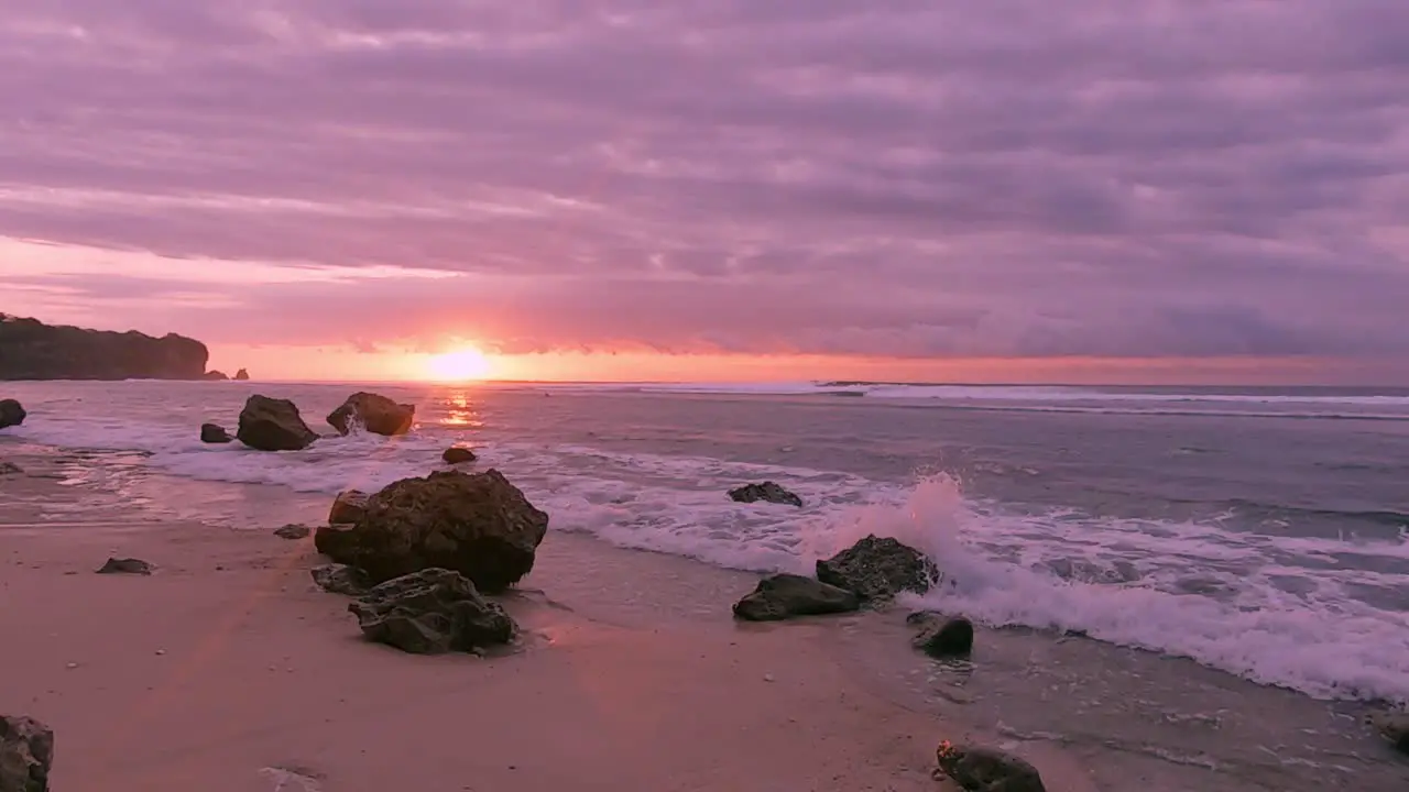 sunset below colorful clouds on a calm rocky beach in Bali