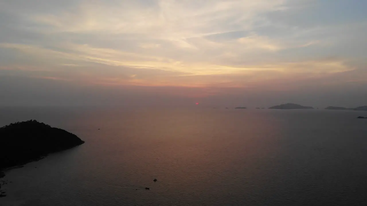 Aerial view of the sunset over the ocean with boats and mountains in the background