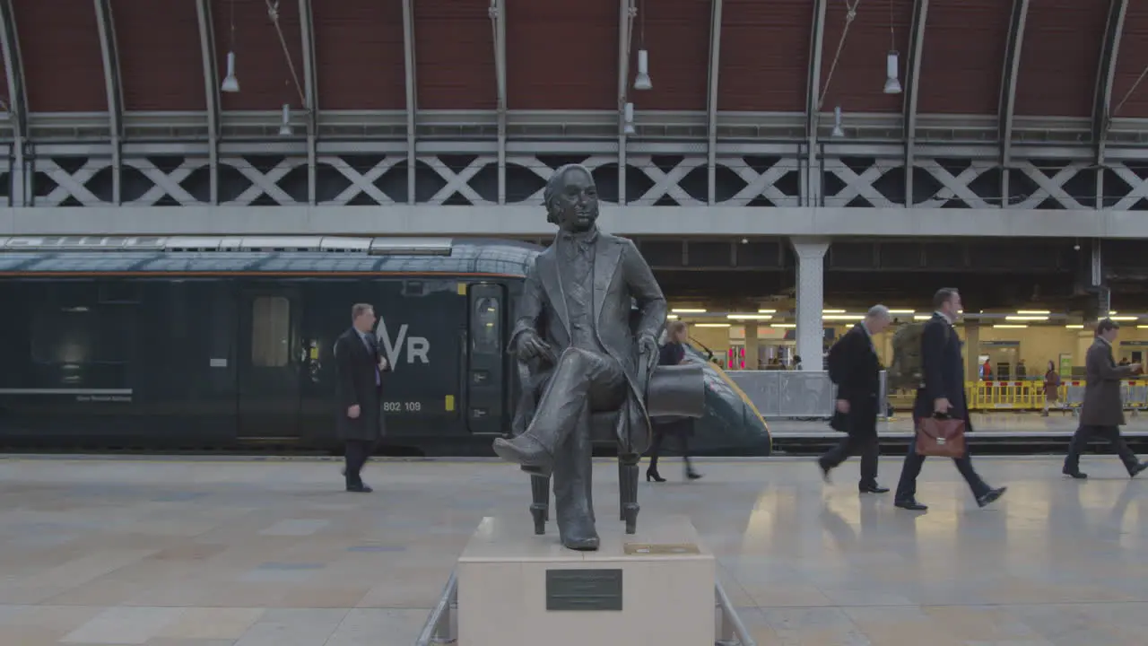 Commuters pass statue on train platform