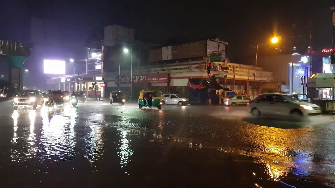 Vehicles passing through MG road junction during heavy rain and flooding