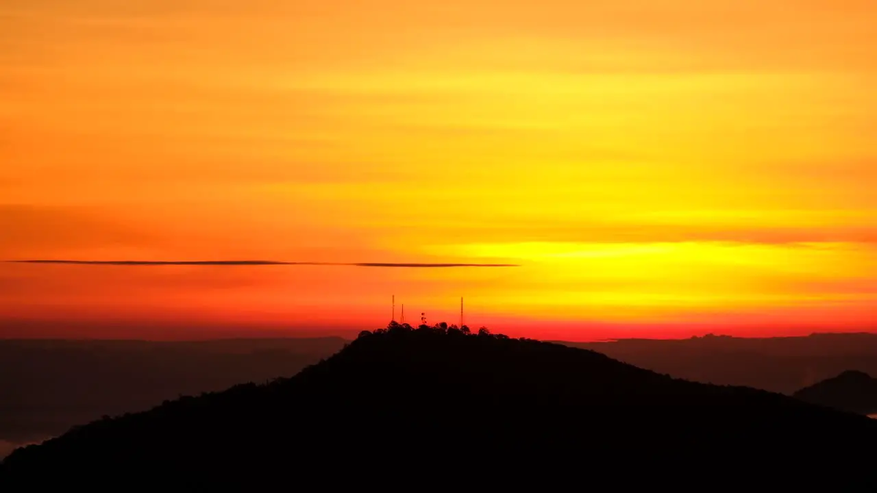 Silhouette of radio towers on mountain top against vibrant sunset background