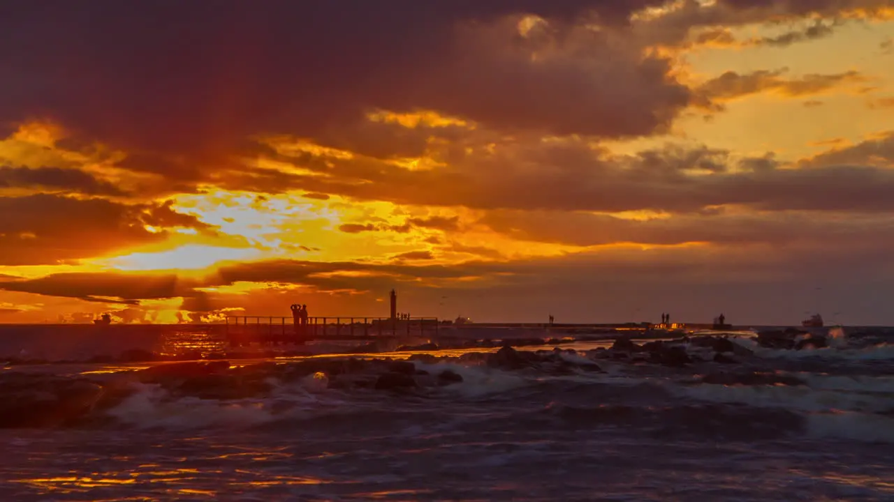 Sunset time-lapse on pier with people walking and ships passing