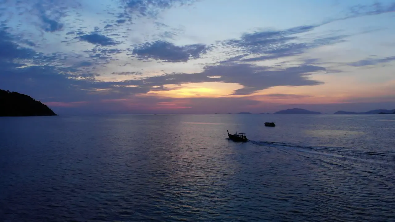 Aerial footage of a tale boat sailing towards the sunset among other boats