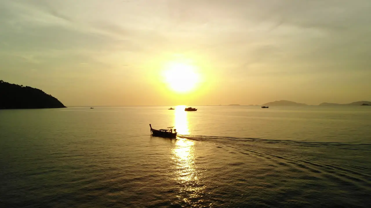 Drone following boat with golden sunset on the backgroud