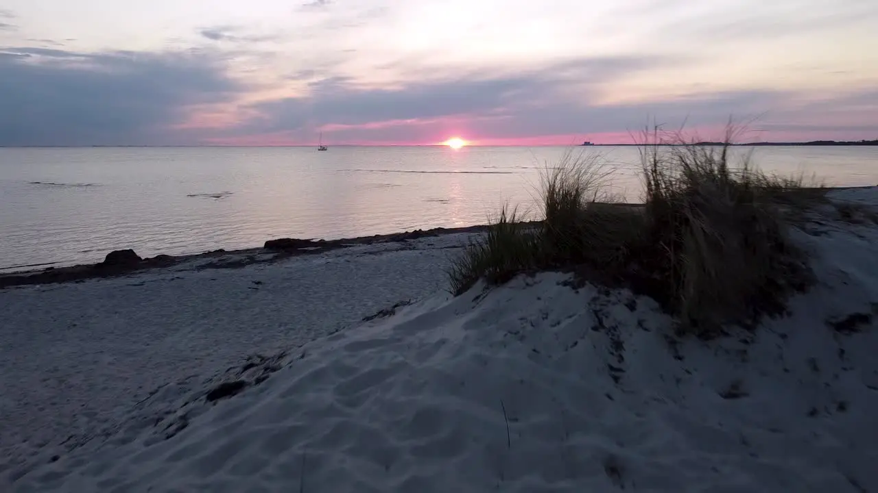 Sunset at a beach in malmö drone flying low and revealing the sunset in the background over the hill