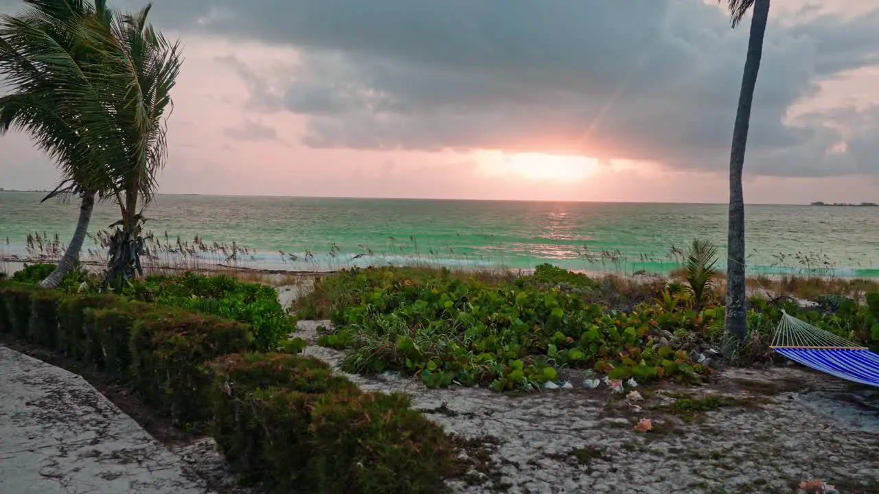 Timelapse on a windy island beach with hammock during sunset