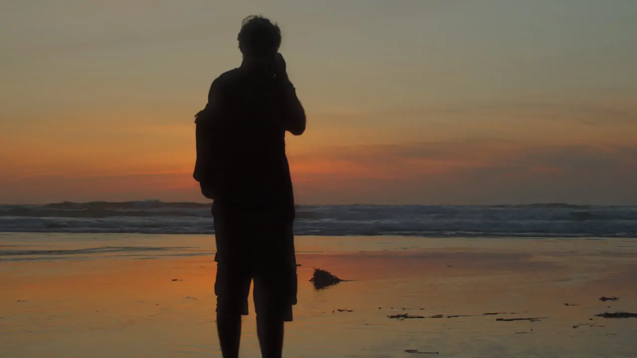 Silhouette photographer taking photo of sunset beach slow reveal