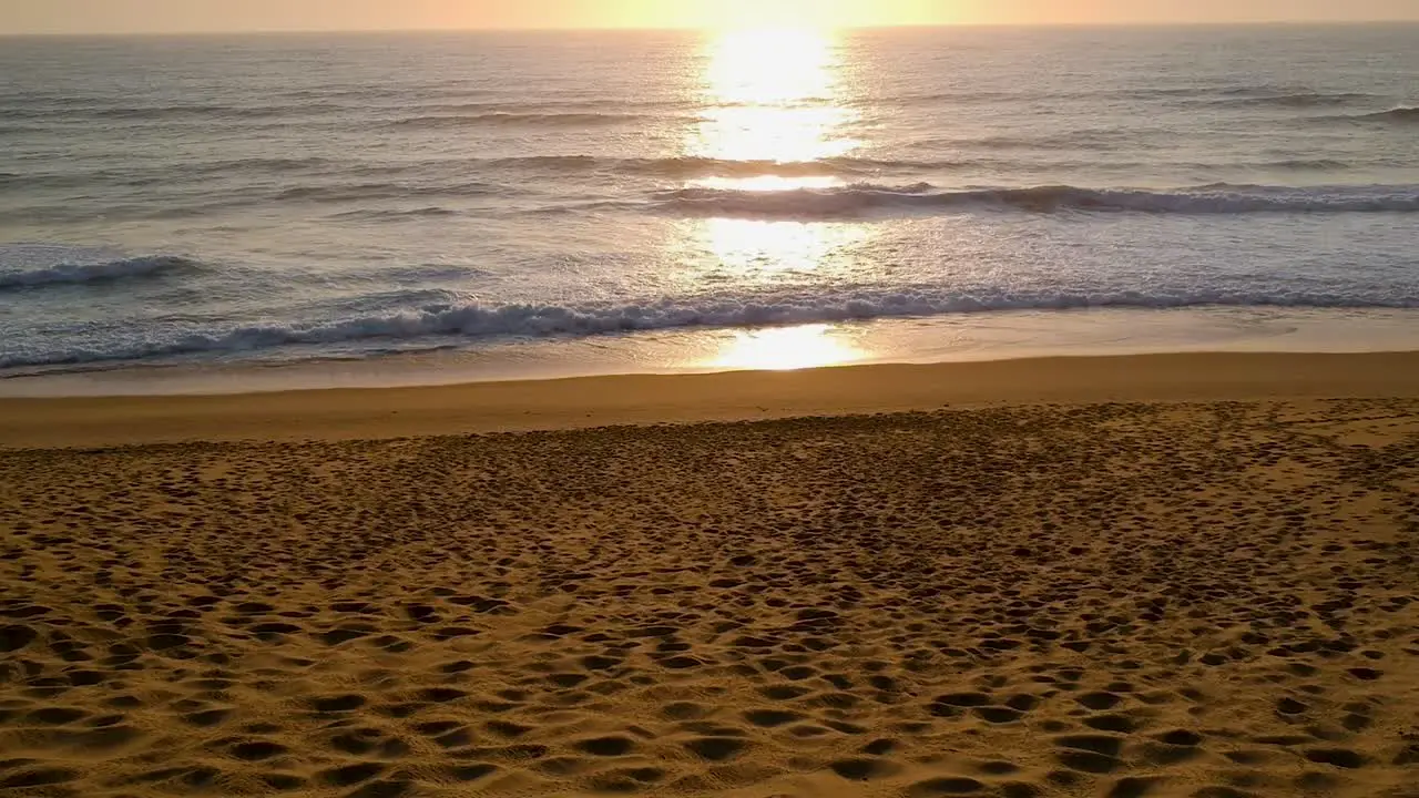 Sunset beach and ocean shot flying slowly towards the sun setting over the ocean