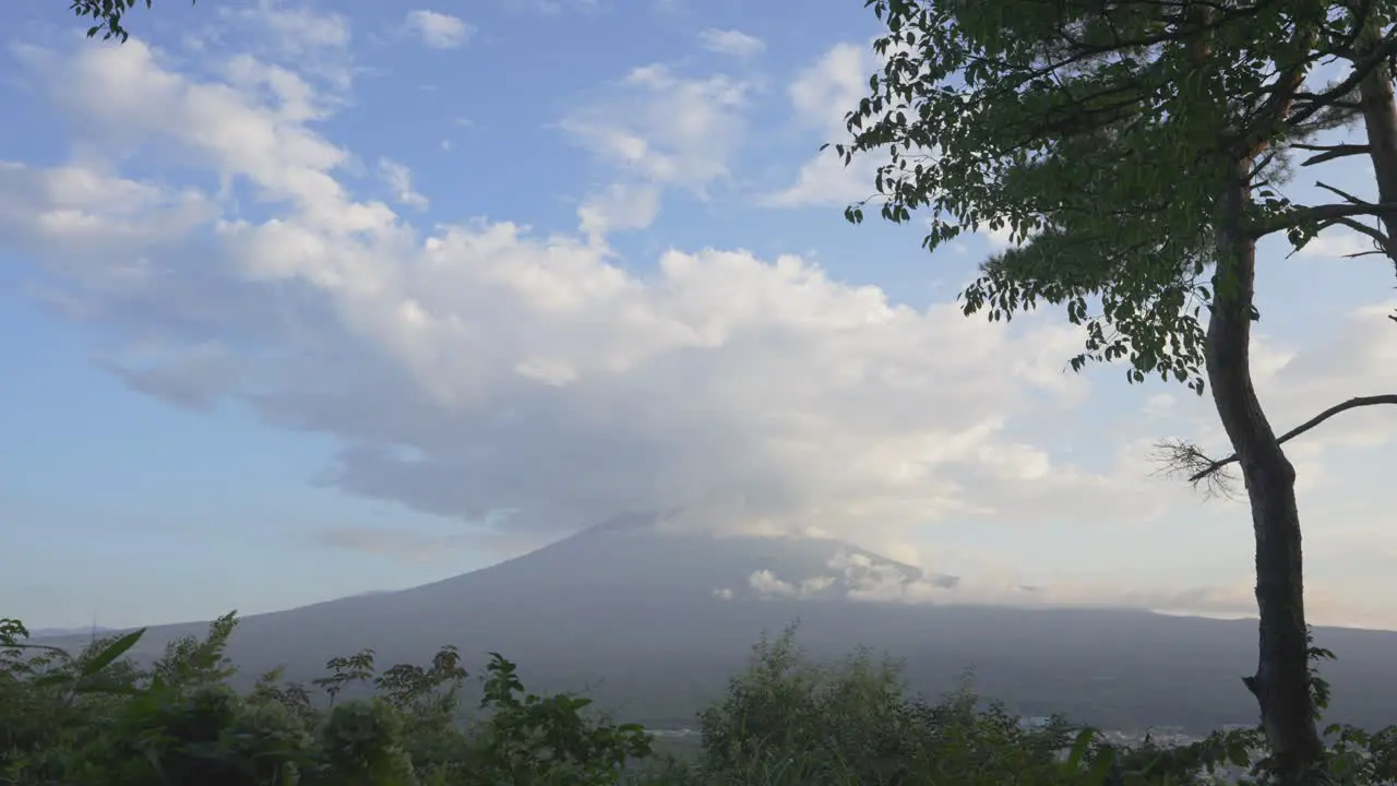 Fuji mountain stands grand with an immobile substantial cloud gracing its summit