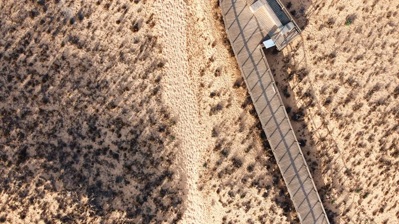 Top view aerial perspective captures the cinematic beauty of Portugal's coastal landscape featuring a walking pathway and a solitary road winding through a desolate terrain