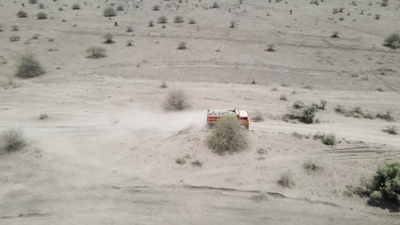 Aerial View of truck driving on rough dirt road transporting rocks