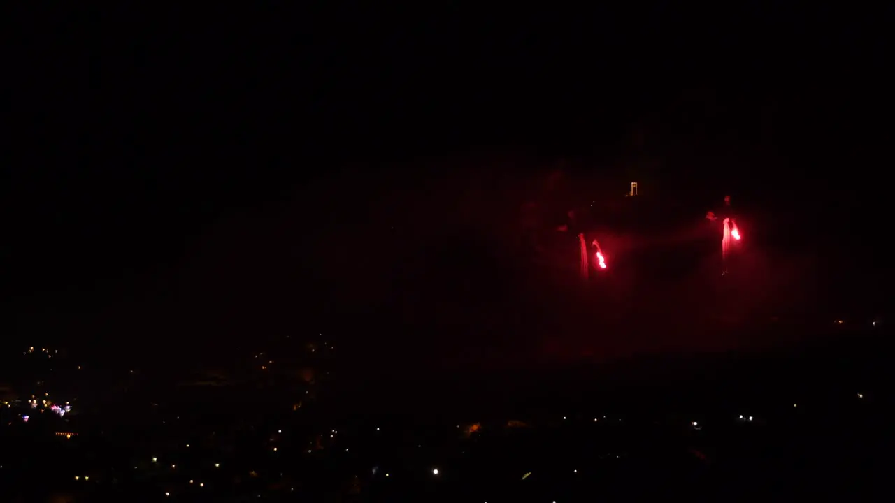 Celebration with red fireworks over a mountain town at night