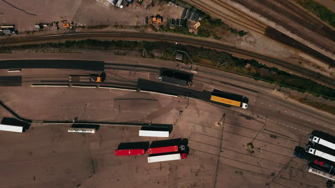 Aerial view above a trucks passing a entrance point at a shipping terminal top down drone shot