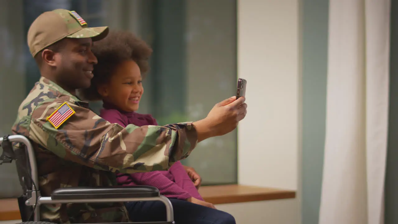 Injured American Soldier Wearing Uniform In Wheelchair Posing For Selfie On Phone With Daughter