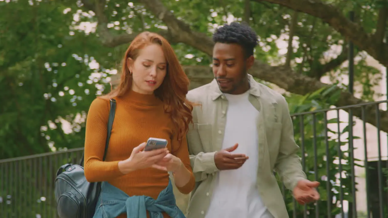 Young Couple Travelling Through City Together Following Directions On Map App On Mobile Phone