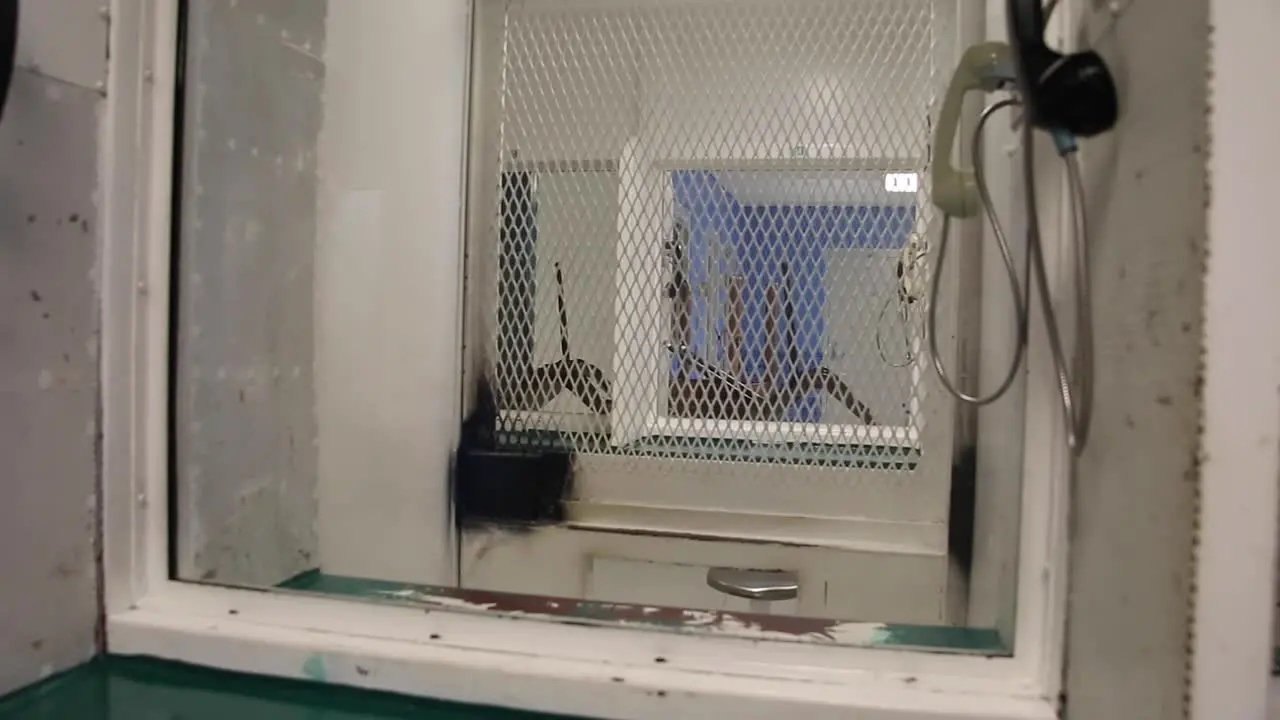 Prison phone booth in jail where prisoners can speak to family members during visitation through glass window