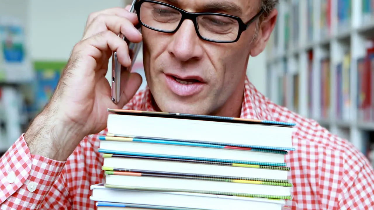 Male teacher talking on mobile phone in library