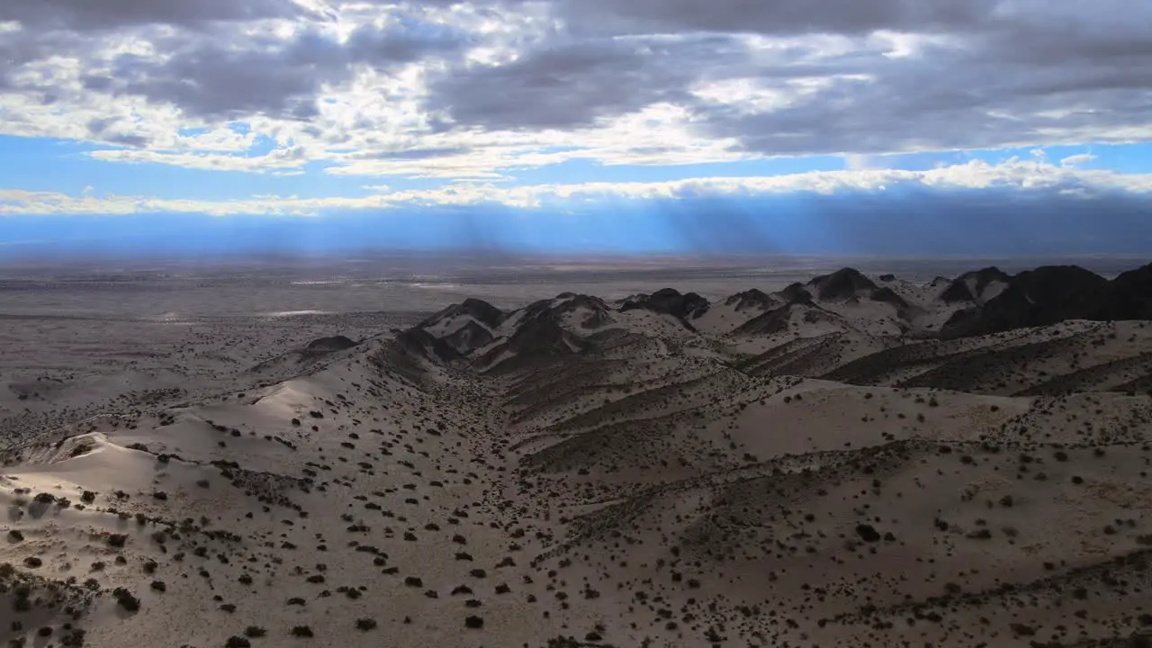 Drone shot flying over the Dunes of Tatón in Catamarca Argentina during overcast conditons with light rays in the distance