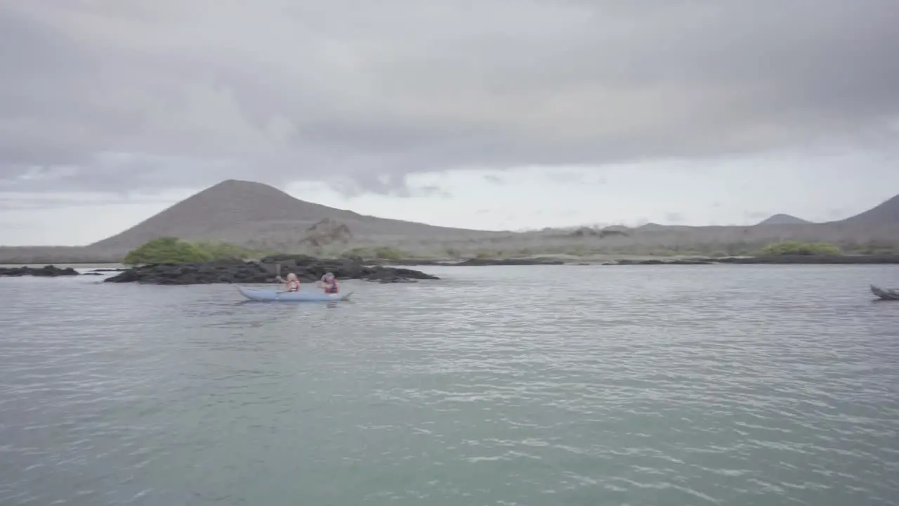 3 kayaks with tourists are kayaking on the ocean of the Galapagos islands