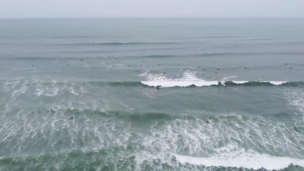 Drone video of surfers on a wave while many other surfers wait for their waves