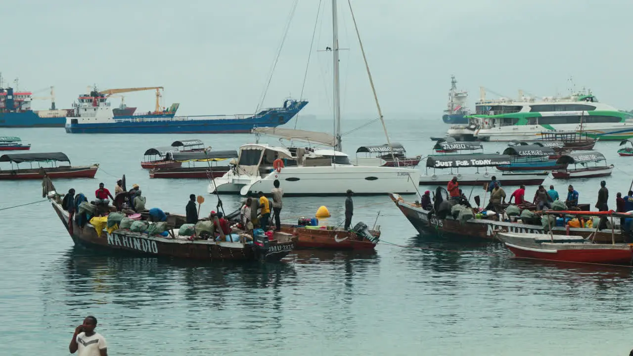 Fishing boats anchor with many African fishermen off Stone Town Beach Zanzibar Tanzania on a cloudy day