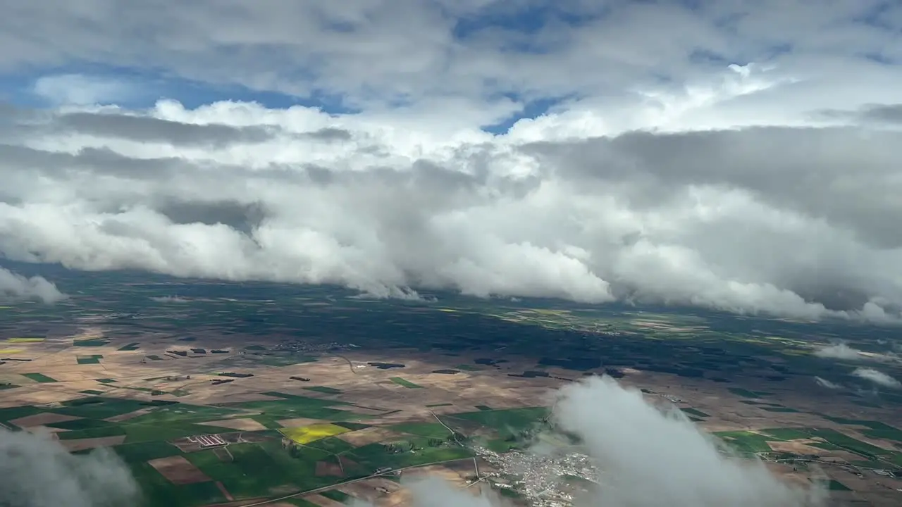 Aerial view from a cockpit of a cludy sky over green and brown fields in central Spain