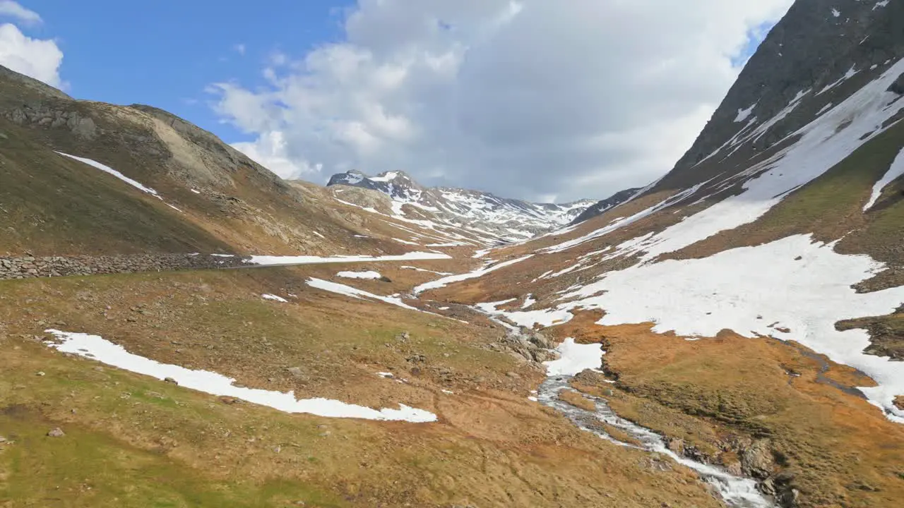 Cinematic drone shot of a snowy mountain top in the alps during summer