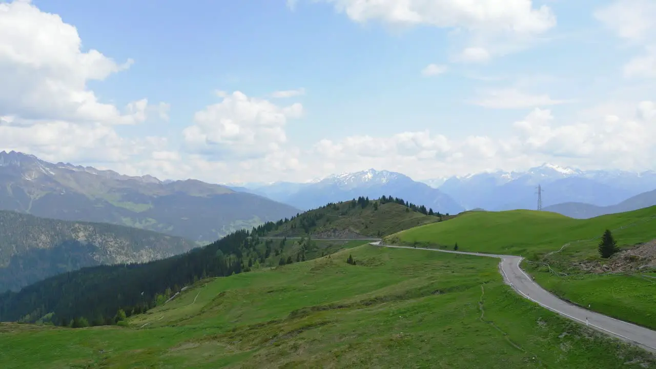 Epic cinematic drone shot of a mountain road with the alps in the background