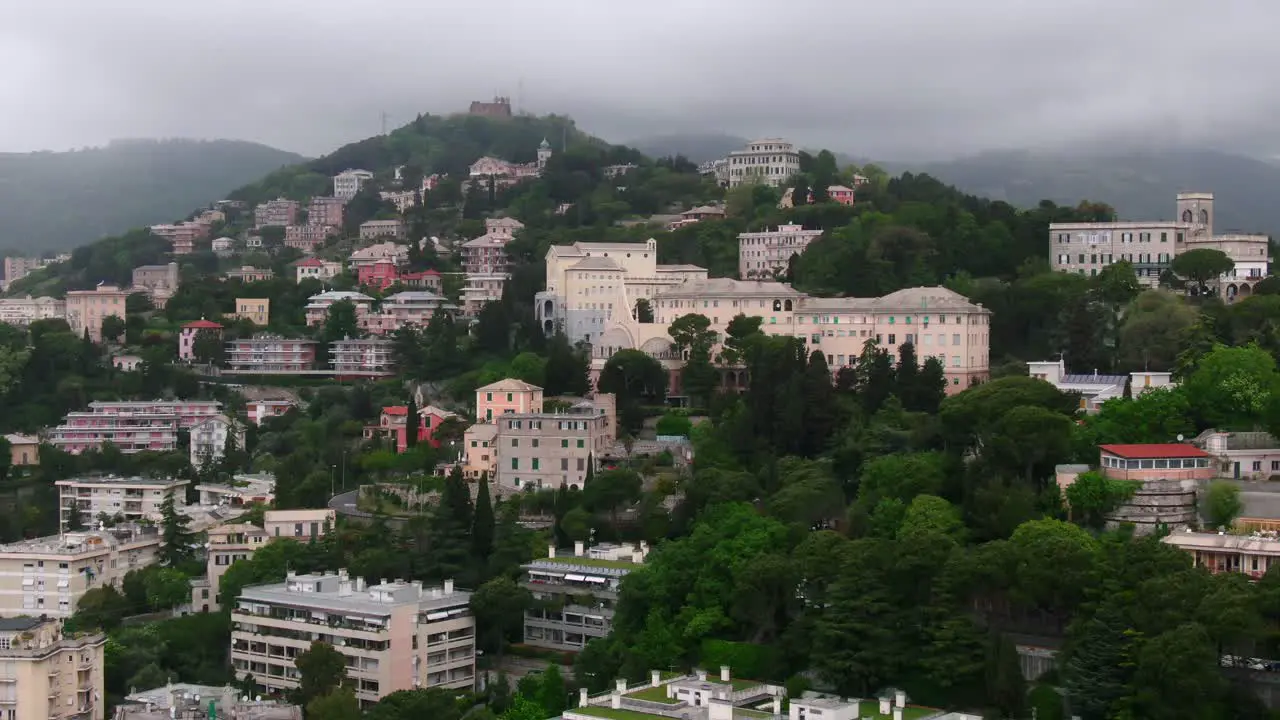 Hillside full of buildings with green vibrant trees on moody stormy day aerial cinematic view