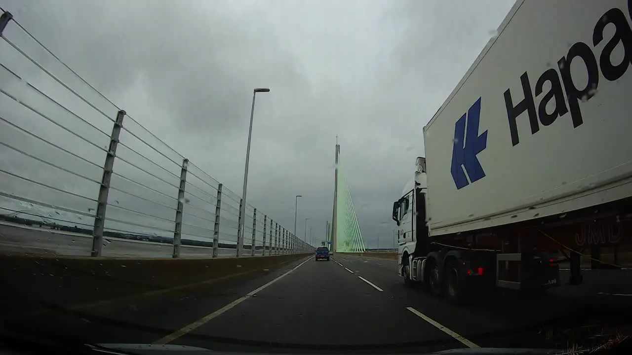 POV dash cam driving towards Mersey gateway bridge in cloudy overcast morning commute traffic