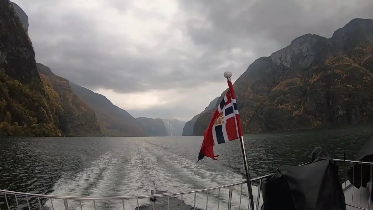 Rear view of ship with Norwegian flag sailing through the Norwegian fjords