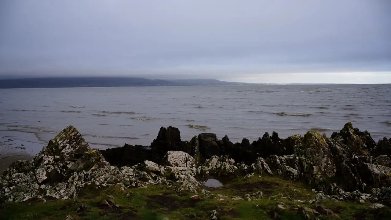 Static view of the rocks and the ocean the waves crashing on the sandy beach in Dundalk Ireland